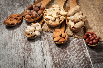 Healthy mix nuts on wooden background. Almonds, hazelnuts, cashews, peanuts, pistachios, brazilian nuts