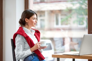 Shot of a young attractive woman having coffee at the cafe sitting relaxed looking at the window...