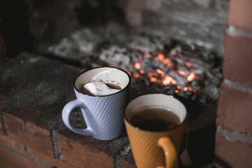 Focused two cups against the background of a fireplace