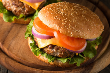 Close-up photo of home made hamburger with beer made of beef, onion, tomato, lettuce, cheese and spices. Fresh burger closeup on wooden rustic table with potato fries and chips.