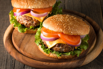 Close-up photo of home made hamburger with beer made of beef, onion, tomato, lettuce, cheese and spices. Fresh burger closeup on wooden rustic table with potato fries and chips.