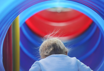 Little curious baby girl look in blue slider in an amusement park