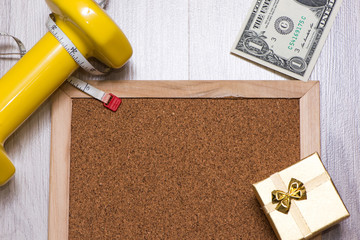 The cork board with dumbbell, gift box and banknote, planning your life for health