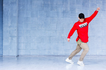 Young handsome break dancer in action. Stylish caucasian rap dancer dancing on grey studio background. Skill, energy and rhythm concept.