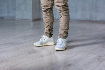 Legs of hip-hop dancer. Stylish hip-hop dancer on grey background, cropped image.