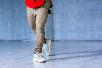 Fototapeta na wymiar Fashion style dancer on grey background. Modern style male hip-hop dancer in movement on grey background.