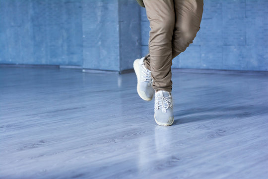 Hip-hop dancer im movement, cropped image. Legs of break dance man in action on grey background.