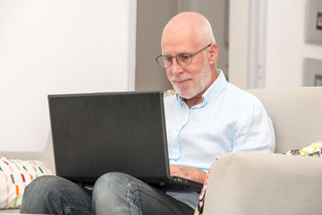 Senior man with laptop sitting in sofa