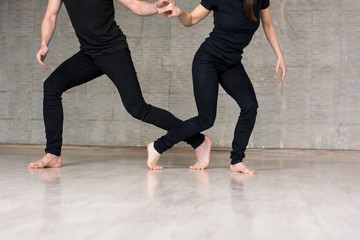 Young couple of dancers in movement. Talented young man and woman practicing dance element on studio background, cropped image.