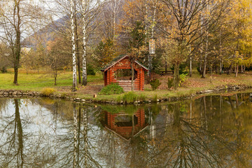 autumn landscape near the water,Scenic autumn landscape colorful foliage in the forest near the river on a cloudy day,a gazebo to relax near the lake