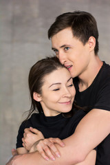 Young loving couple, studio shot. Young handsome man hugging his girlfriend on studio background. Beautiful couple of young lovers.