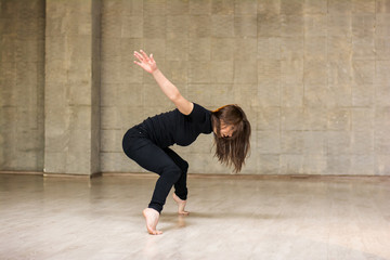 Beautiful young dancer in movement. Young slim woman dancer dancing contemporatry dance on studio background. Flexibility and rhythm in modern dance.