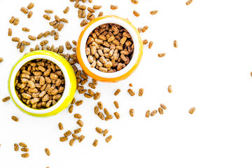 Dry pet food in bowls on white background top view copyspace