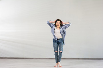 Young pretty dancer posing in studio. Young energetic girl holding hands behind her head performing contentemporary dance.