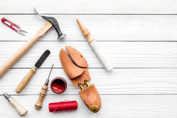 Fototapeta na wymiar Shoe repair. Wooden last, hammer, awl, knife, thread on white wooden background top view copyspace