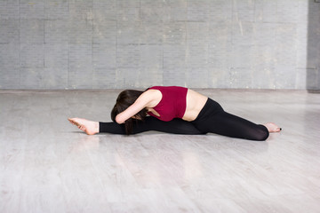 Young woman stretching in studio. Slim girl practicing gymnastics element on studio background.