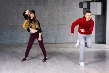 Obraz na płótnie Canvas Couple of talented dancers performing hip-hop. Guy and girl dancing contemporary dance i studio. School of hip-hop culture.