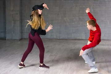 Poster Hip-hop dancers in action. Young couple of casual dancers performing modern dance on studio background. School of dance art.