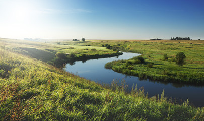 Fototapeta na wymiar Sunny summer landscape with river.Green meadows and fields at sunrise.