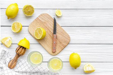 Make lemonade at home. Lemons, juicer, glass, knife, cutting board on white wooden background top...