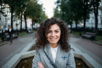  symmetrical portrait of a curly girl. Brunette in the park