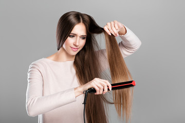 woman ironing hair with hair iron. 