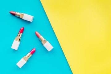 Lipsticks assorted colors on yellow and blue background top view copyspace