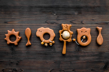 Cute wooden handmade toys for newborn on dark wooden background top view copyspace
