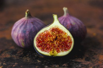 Half of fresh ripe figs on rusty metal surface.