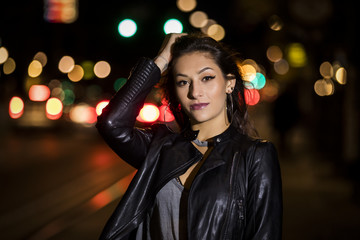 Lifestyle portrait of an attractive woman in front of traffic lights at night
