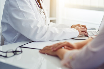 Male doctor with patient sitting at desk and writing on laptop. Consultation in the office.