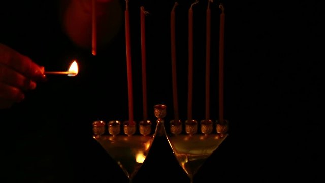 the woman inserts candles with her hand into the candlestick for chanukah. static camera