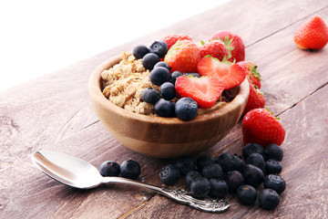 Bowl of homemade granola with  fresh berries on wooden background.