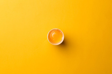 White egg and egg yolk on the yellow background. topview