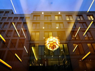 Spiegelung eines Bürogebäudes in der Scheibe des gegenüberliegenden Hauses mit Deckenleuchte und...