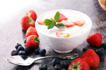 Homemade yogurt with fresh strawberry on a grey background.