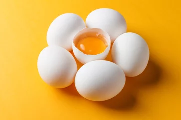 Keuken spatwand met foto White eggs and egg yolk on the yellow background © masanyanka
