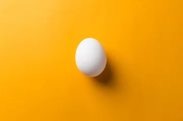 Foto op Plexiglas White egg and egg yolk on the yellow background. topview © masanyanka