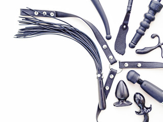 Various toys for adults (harness, whip, dildo, vibrator, butt plug, slapstick and others) are on a white background. Image for sex shop advertising, discounts and promotions
