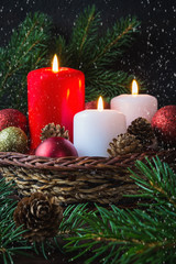 Obraz na płótnie Canvas Christmas red balls, candles, spruce branches, wreath and snowflakes on a dark background Decoration for a New Year's holiday with a copy space