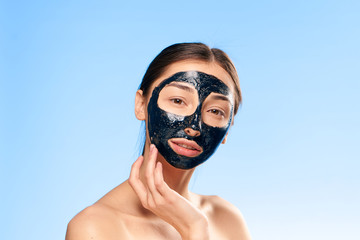 Black cosmetic face mask, coal face mask, girl on a blue background