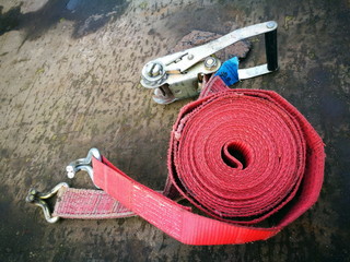 Aufgerollter roter Spanngurt mit Spannvorrichtung auf der Pritsche eines Lastwagen in der...