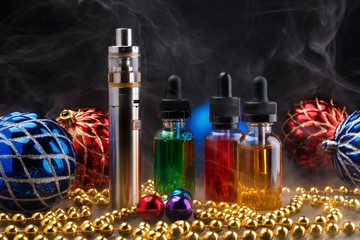 Electronic cigarette with vape liquids within vapor and christmas decorations on black background