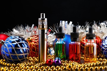 Electronic cigarette with vape liquids and christmas decorations on dark background