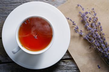 View from above on the white cup of hot black tea with lavender on the old wooden table.
