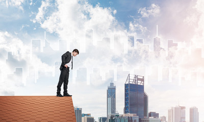 Businessman looking down from roof and modern cityscape at background. Mixed media