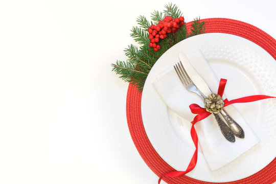 Christmas Table Setting With White Dishware, Silverware And Red Decorations On White Background. Top View.