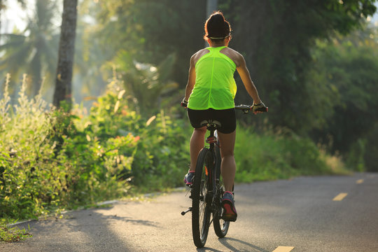 Young  woman cyclist cycling on tropical forest trail
