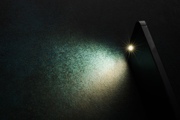 Lantern smartphone shines on a dark background. - obrazy, fototapety, plakaty