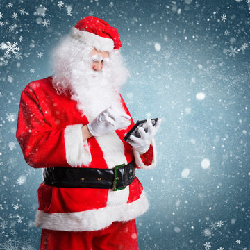 Weihnachtsmann checkt Tablet vor winterlichem Hintergrund